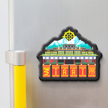 Decorative skkim magnet with a colorful design of a building and a mountain on a refrigerator.