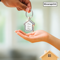 Keychain with 'Home Sweet Home' text held by a hand, with a blurred background and 'Nivaraprint' branding.