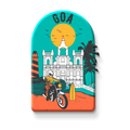 Decorative magnet with a design of a building, palm trees, and a person on a motorcycle on a metallic surface.