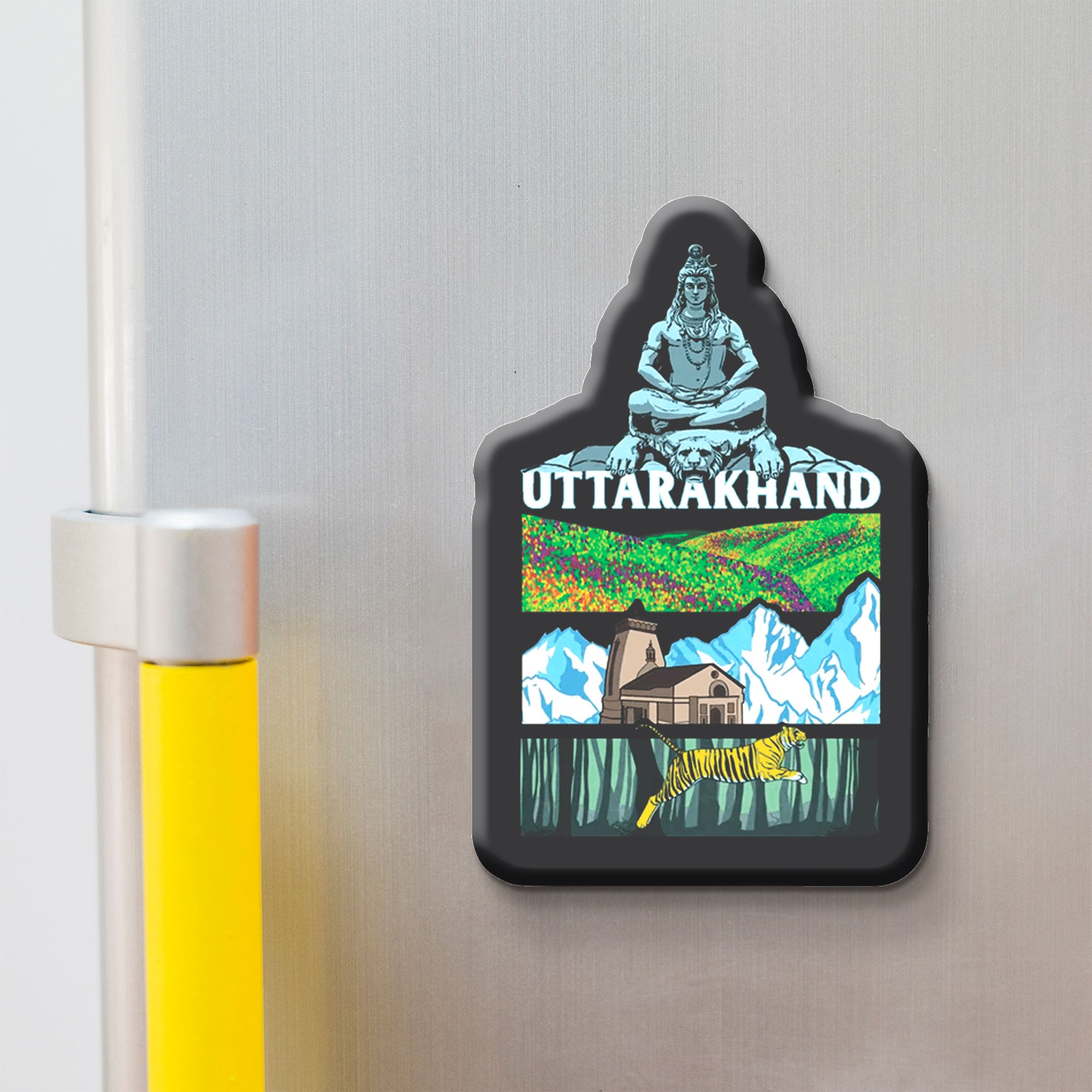 Fridge magnet with 'Uttarakhand' design featuring a mountain, house, and nature on a metallic surface.