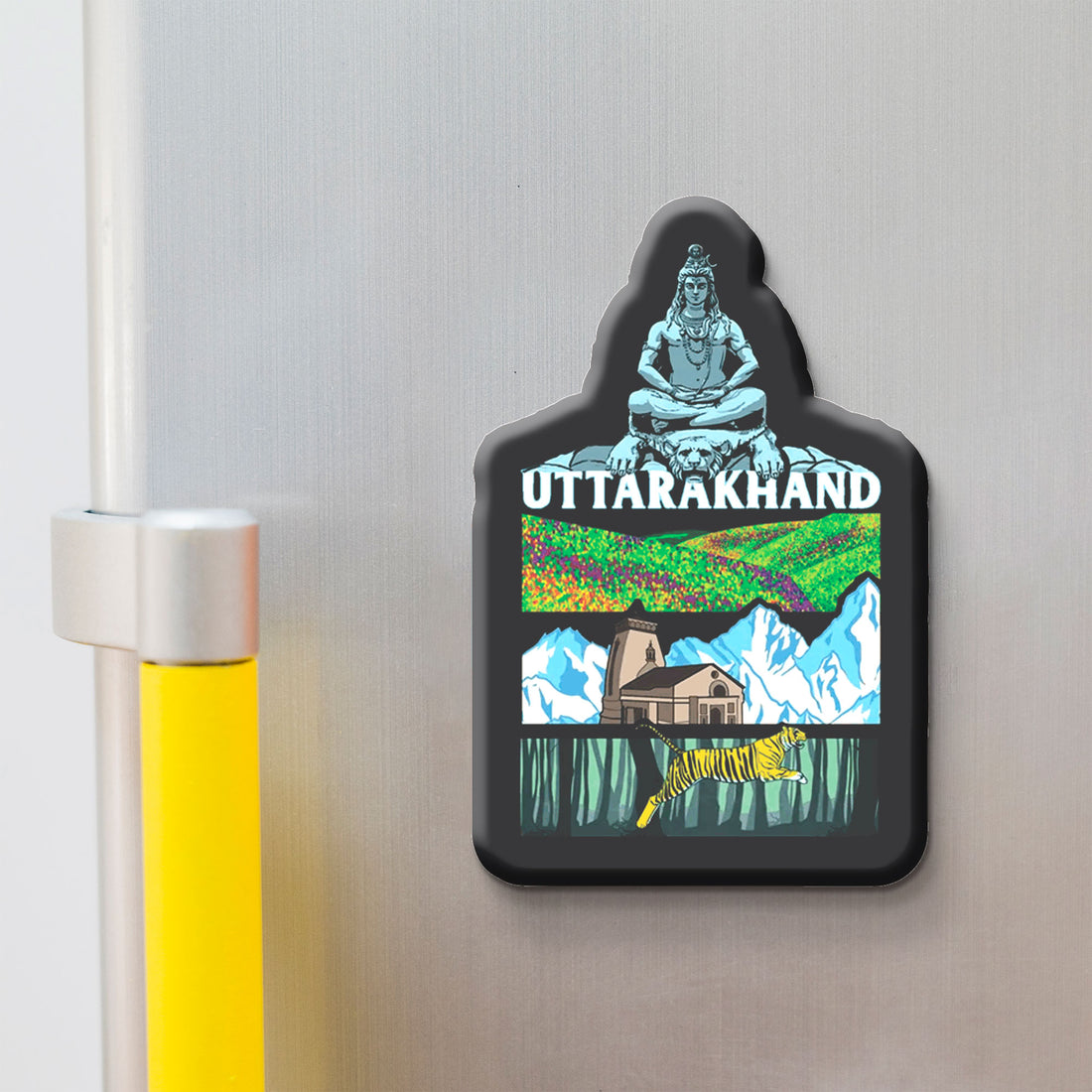 Fridge magnet with 'Uttarakhand' design featuring a mountain, house, and nature on a metallic surface.