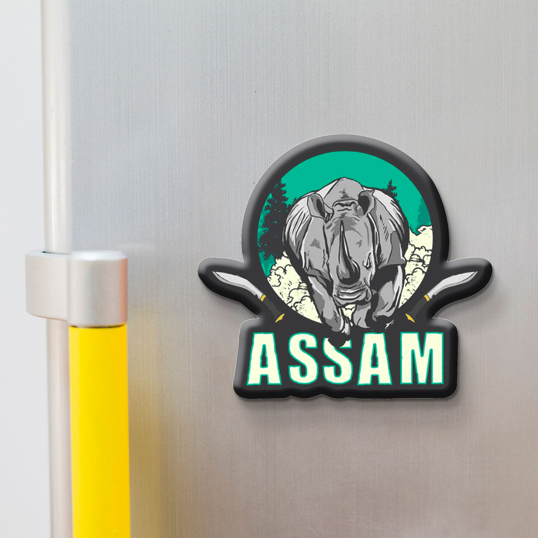 Fridge magnet with a rhinoceros design and 'Assam' text on a metallic surface.