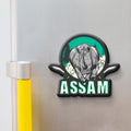 Fridge magnet with a rhinoceros design and 'Assam' text on a metallic surface.